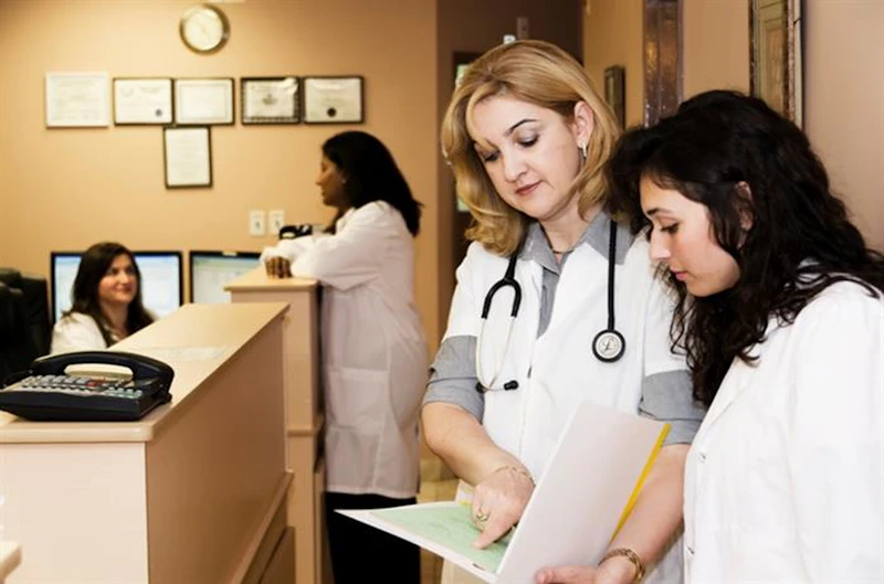 Recepção de clínica com profissionais de saúde conferindo um documento